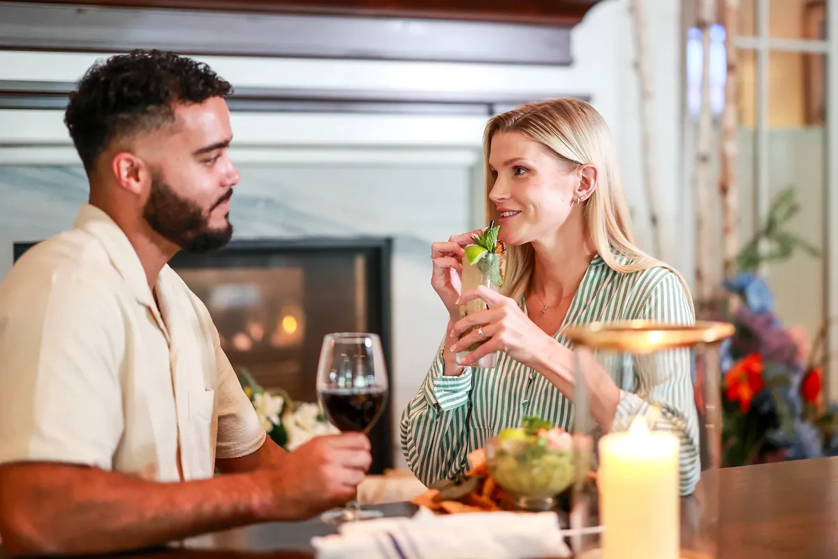 A couple sharing drinks at a candlelit table by the fireplace