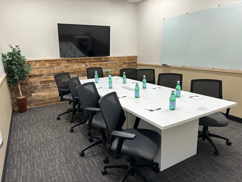 Conference table set with notepads, water, and a presentation screen